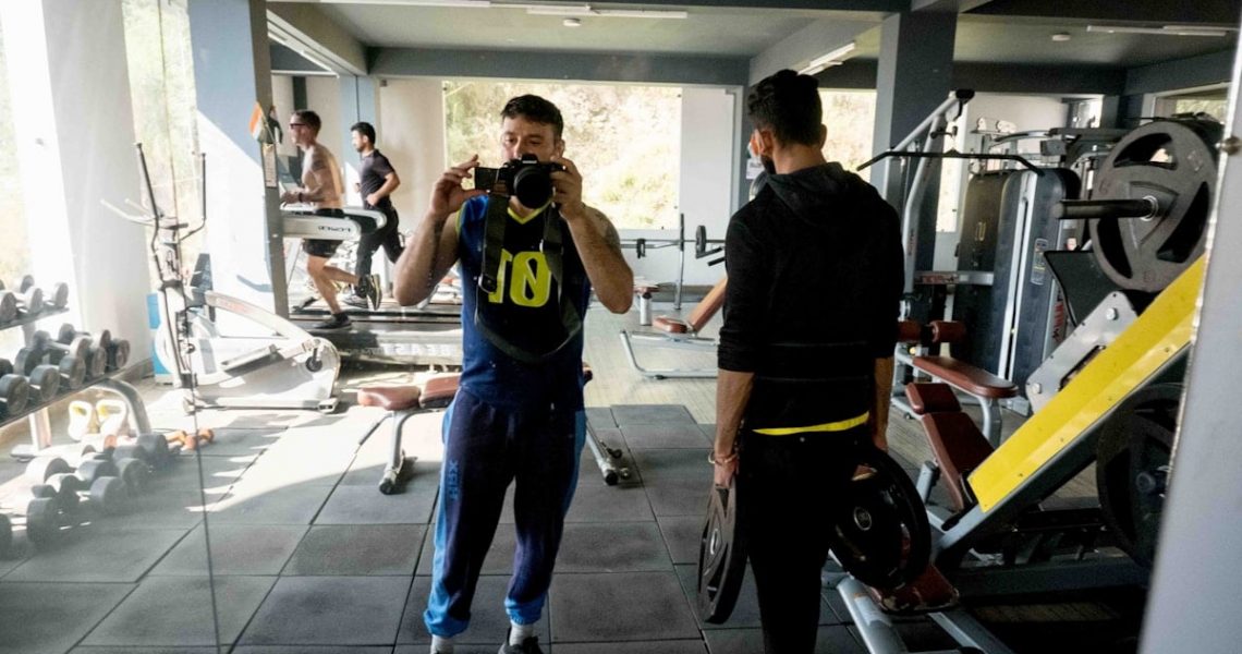 a man taking a picture of another man in a gym